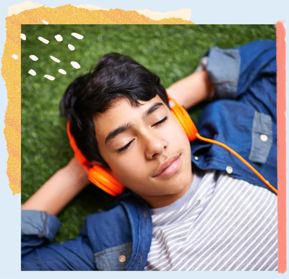 Boy listening to music lying on grass